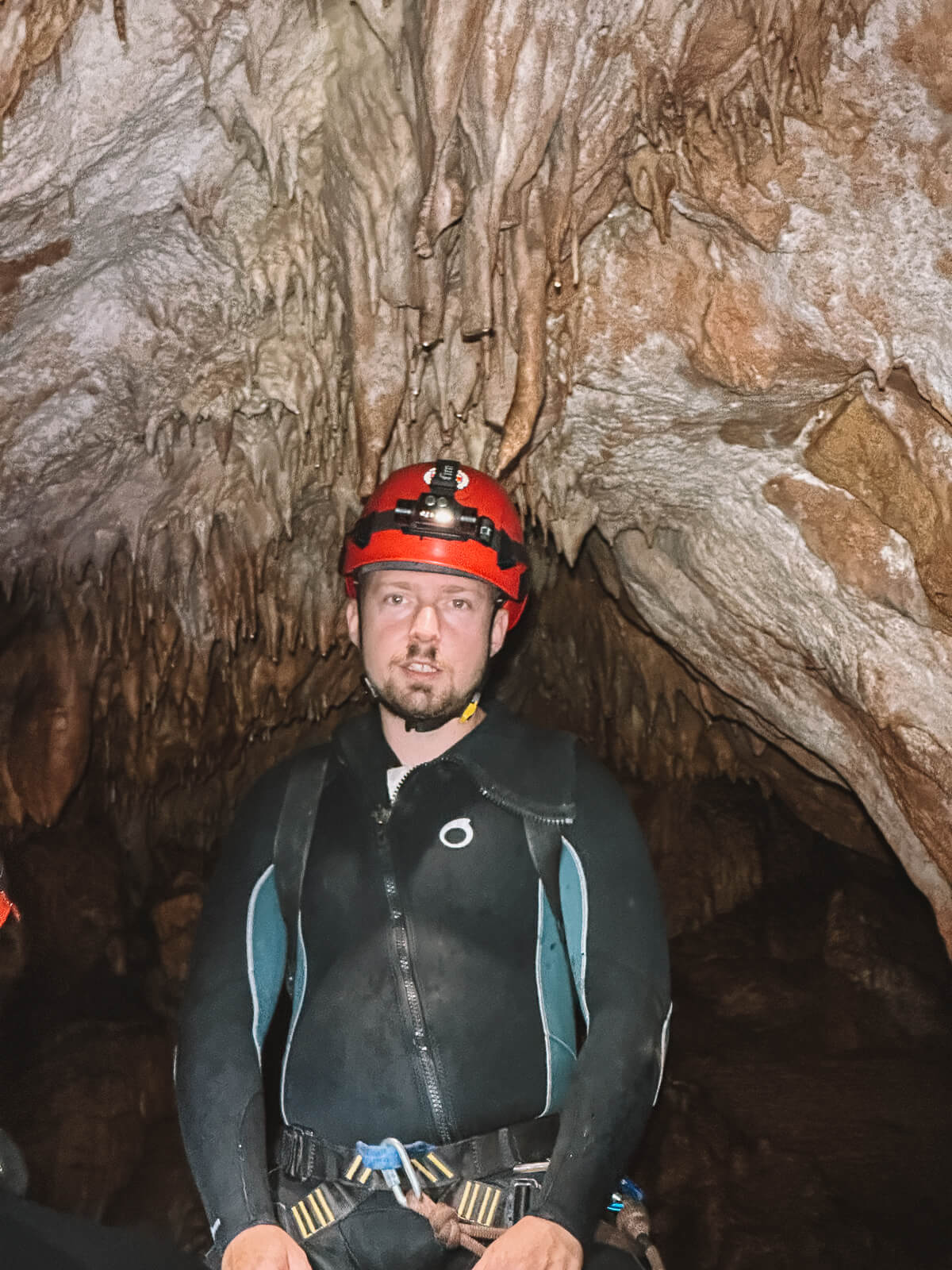 Ein Tour Guide mit einem roten Helm steht in einer Höhle