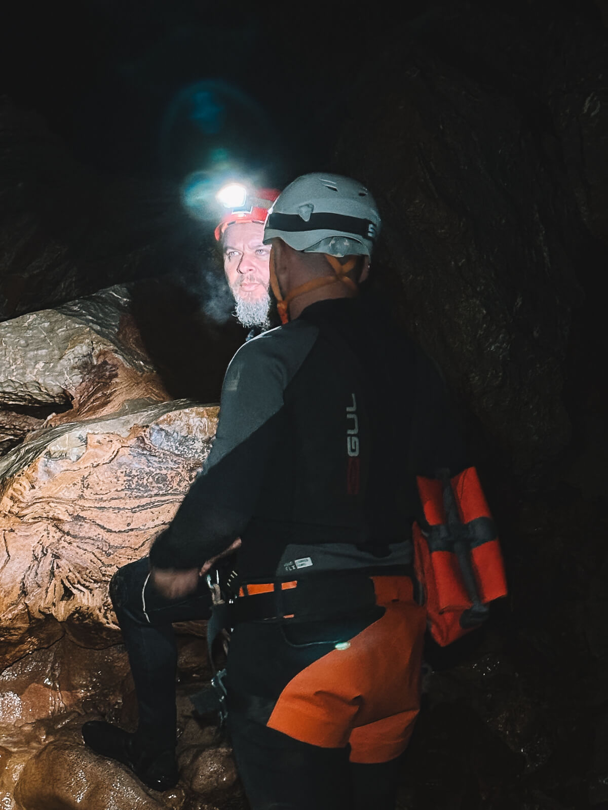 Zwei Teilnehmer einer Höhlentour unterhalten sich, beide tragen einen Helm und Wetsuit